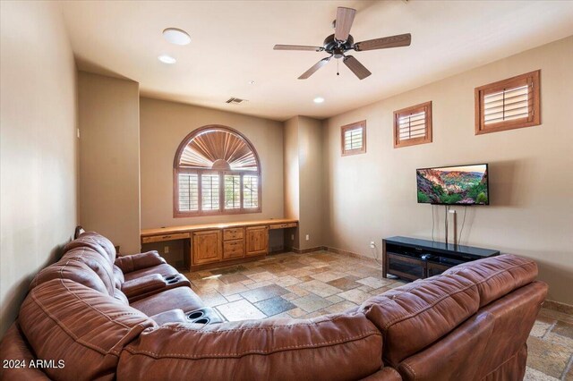 living area featuring built in desk, recessed lighting, stone tile flooring, a ceiling fan, and baseboards