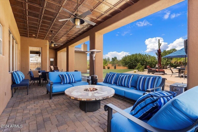 view of patio with ceiling fan and an outdoor living space with a fire pit