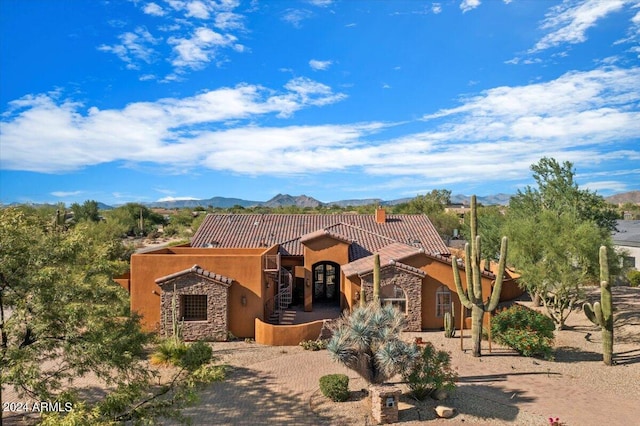 mediterranean / spanish-style home featuring stone siding, a tiled roof, a mountain view, and stucco siding