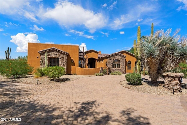 view of front of property with stone siding, driveway, a tiled roof, and stucco siding