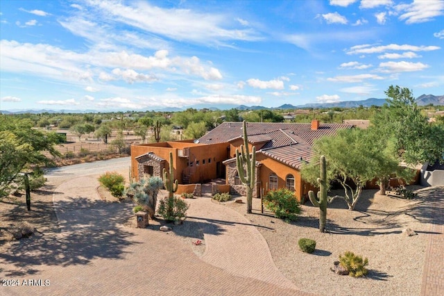 pueblo revival-style home featuring a tiled roof, decorative driveway, and a mountain view