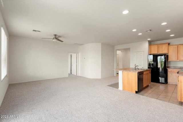 kitchen with black appliances, an island with sink, light colored carpet, and ceiling fan