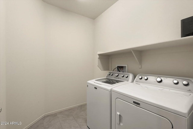 clothes washing area featuring light tile patterned flooring and separate washer and dryer