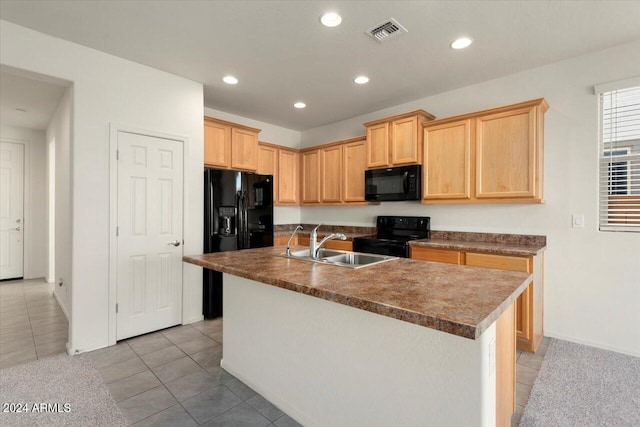 kitchen featuring a center island with sink, light tile patterned floors, light brown cabinetry, black appliances, and sink