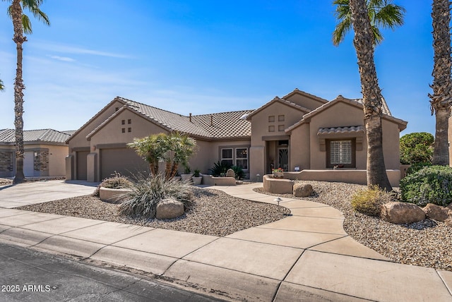 view of front of house with concrete driveway, an attached garage, a tile roof, and stucco siding