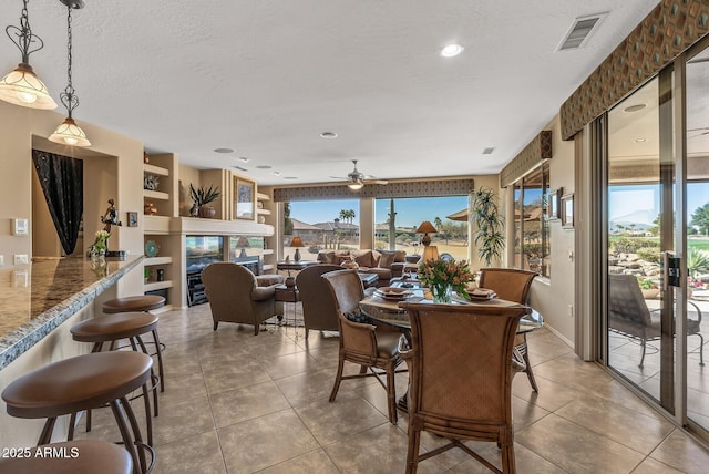 dining room featuring a healthy amount of sunlight, light tile patterned floors, visible vents, and a textured ceiling