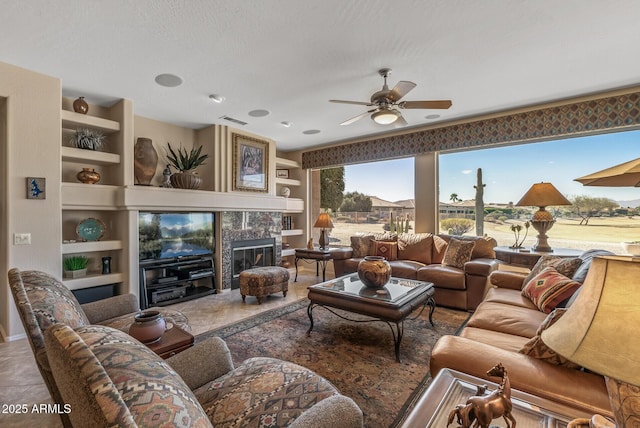 tiled living area with ceiling fan, built in shelves, a tile fireplace, and visible vents