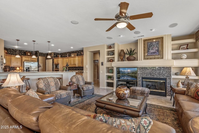 living room with recessed lighting, built in shelves, visible vents, and a tile fireplace