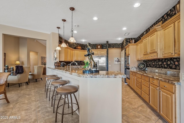 kitchen with a breakfast bar, pendant lighting, tasteful backsplash, appliances with stainless steel finishes, and light stone countertops