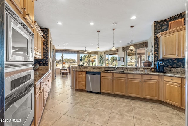 kitchen featuring light tile patterned flooring, dark stone counters, stainless steel appliances, and decorative light fixtures