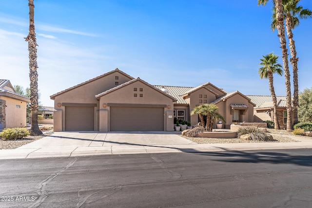 view of front of property with an attached garage, a tile roof, concrete driveway, and stucco siding