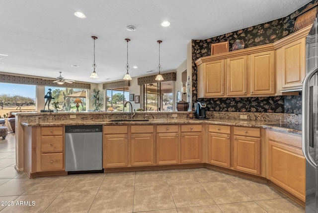 kitchen with light tile patterned floors, stainless steel appliances, hanging light fixtures, a sink, and wallpapered walls