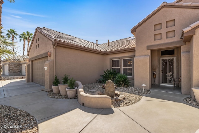 exterior space featuring driveway, a tiled roof, an attached garage, and stucco siding