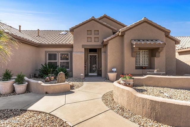 view of front of home with a patio area, a tiled roof, and stucco siding