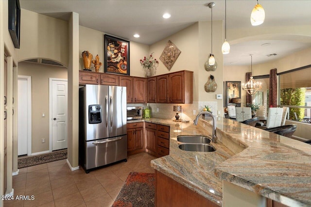 kitchen featuring light stone countertops, sink, appliances with stainless steel finishes, and pendant lighting