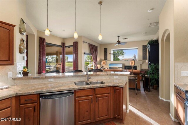 kitchen with light stone countertops, decorative backsplash, sink, and stainless steel dishwasher