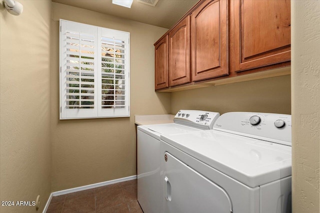 clothes washing area featuring dark tile patterned flooring, cabinets, and washer and clothes dryer