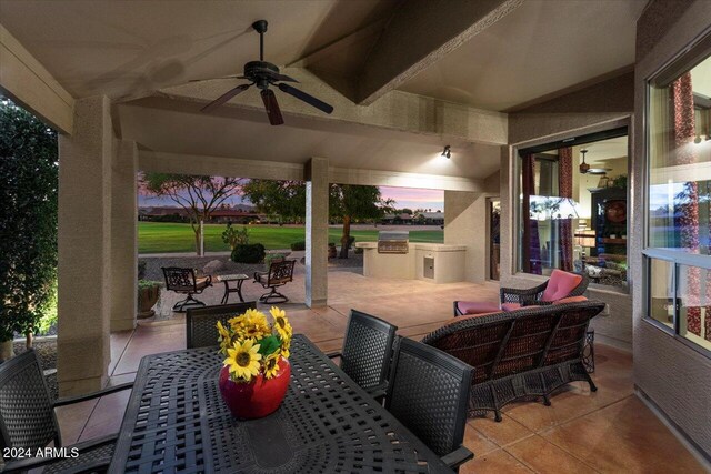 patio terrace at dusk featuring exterior kitchen, an outdoor living space, and ceiling fan