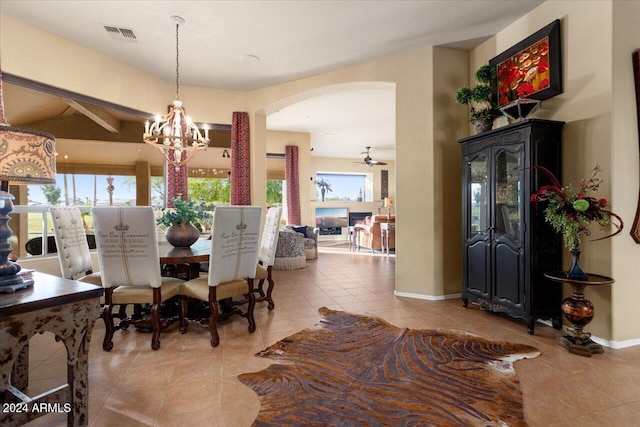 dining space featuring beam ceiling, light tile patterned floors, and ceiling fan with notable chandelier