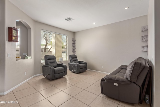 living area featuring light tile patterned floors, baseboards, recessed lighting, and arched walkways