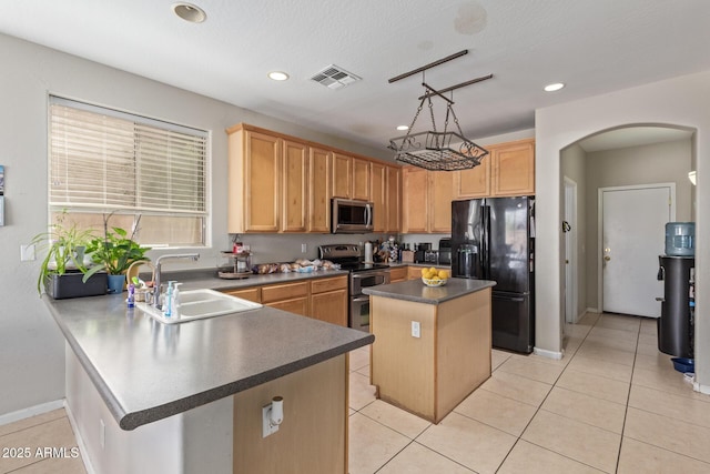 kitchen featuring appliances with stainless steel finishes, a sink, arched walkways, dark countertops, and a kitchen island