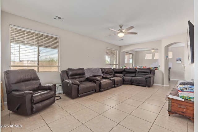 living area with a ceiling fan, arched walkways, and light tile patterned floors