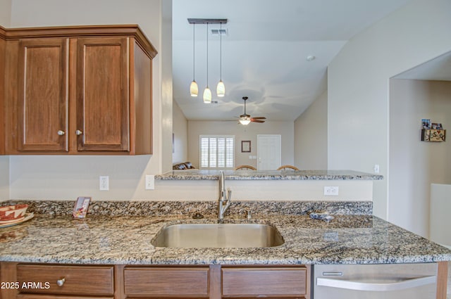 kitchen with vaulted ceiling, light stone counters, brown cabinets, and a sink