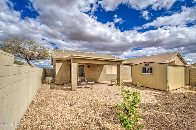 rear view of house featuring stucco siding, an outbuilding, a fenced backyard, and a patio area