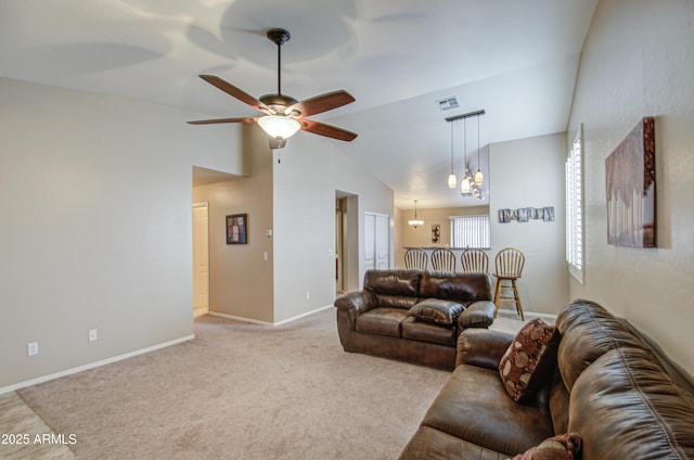 living area with carpet, visible vents, baseboards, high vaulted ceiling, and ceiling fan with notable chandelier