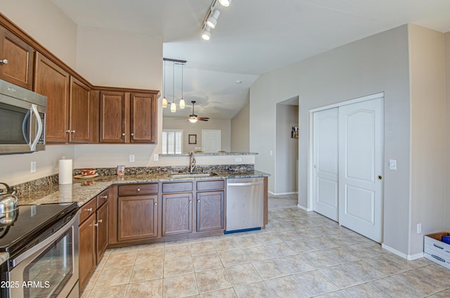 kitchen with lofted ceiling, stone counters, appliances with stainless steel finishes, light tile patterned flooring, and a sink