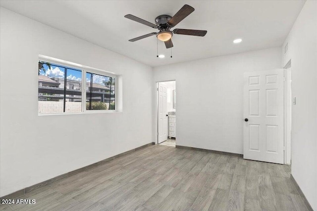 unfurnished bedroom with ceiling fan, ensuite bathroom, and light hardwood / wood-style flooring