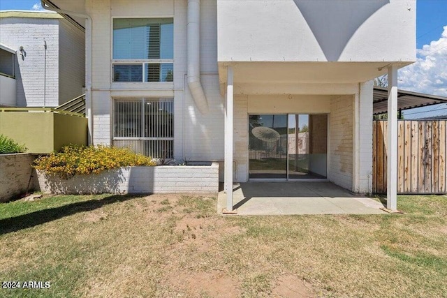 rear view of property with a patio, brick siding, a lawn, and fence