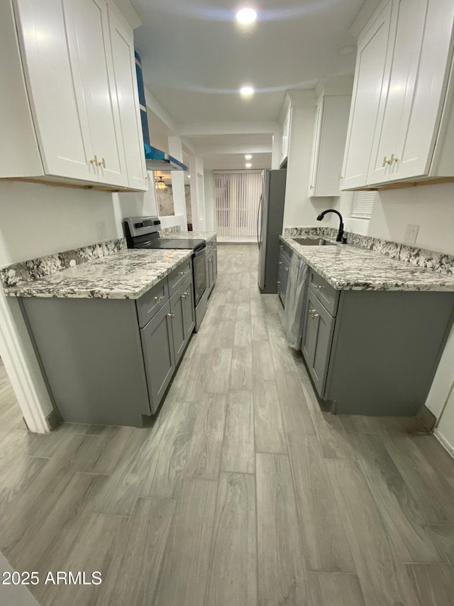 kitchen featuring light stone countertops, appliances with stainless steel finishes, white cabinetry, and a sink