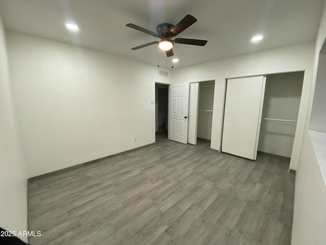 unfurnished bedroom with ceiling fan, recessed lighting, visible vents, light wood-style floors, and multiple closets