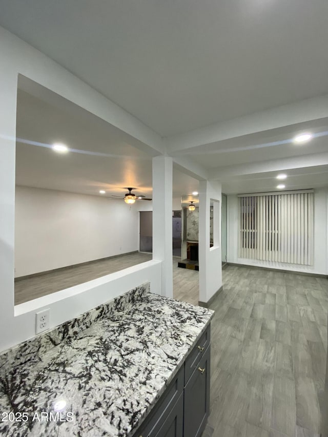 kitchen featuring light stone countertops, light wood-style flooring, open floor plan, and dark cabinets