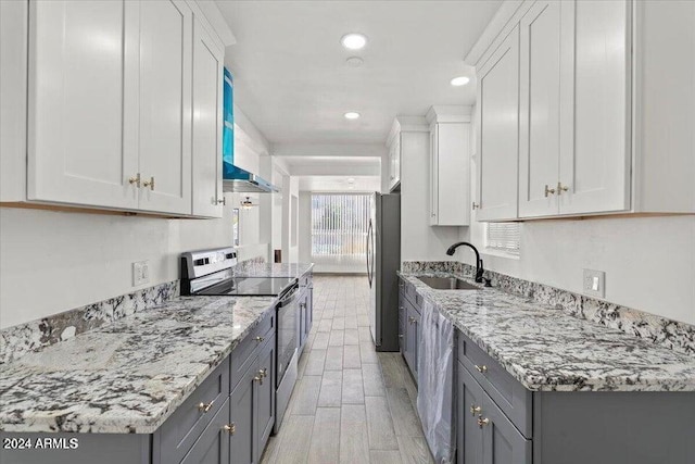 kitchen featuring white cabinetry, appliances with stainless steel finishes, light stone counters, and a sink