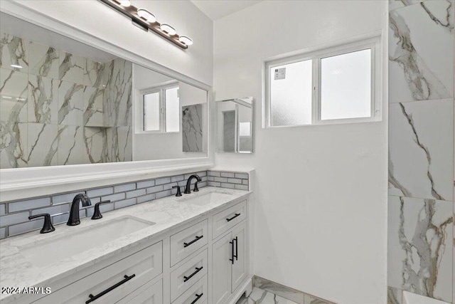 bathroom with marble finish floor, double vanity, a sink, and decorative backsplash