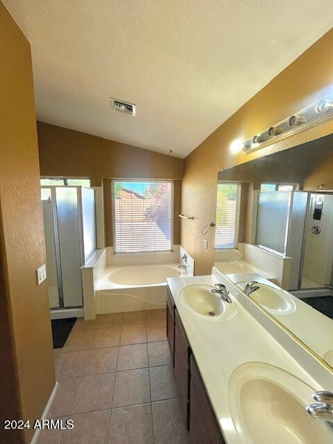 bathroom with tile patterned floors, a textured ceiling, shower with separate bathtub, and vaulted ceiling