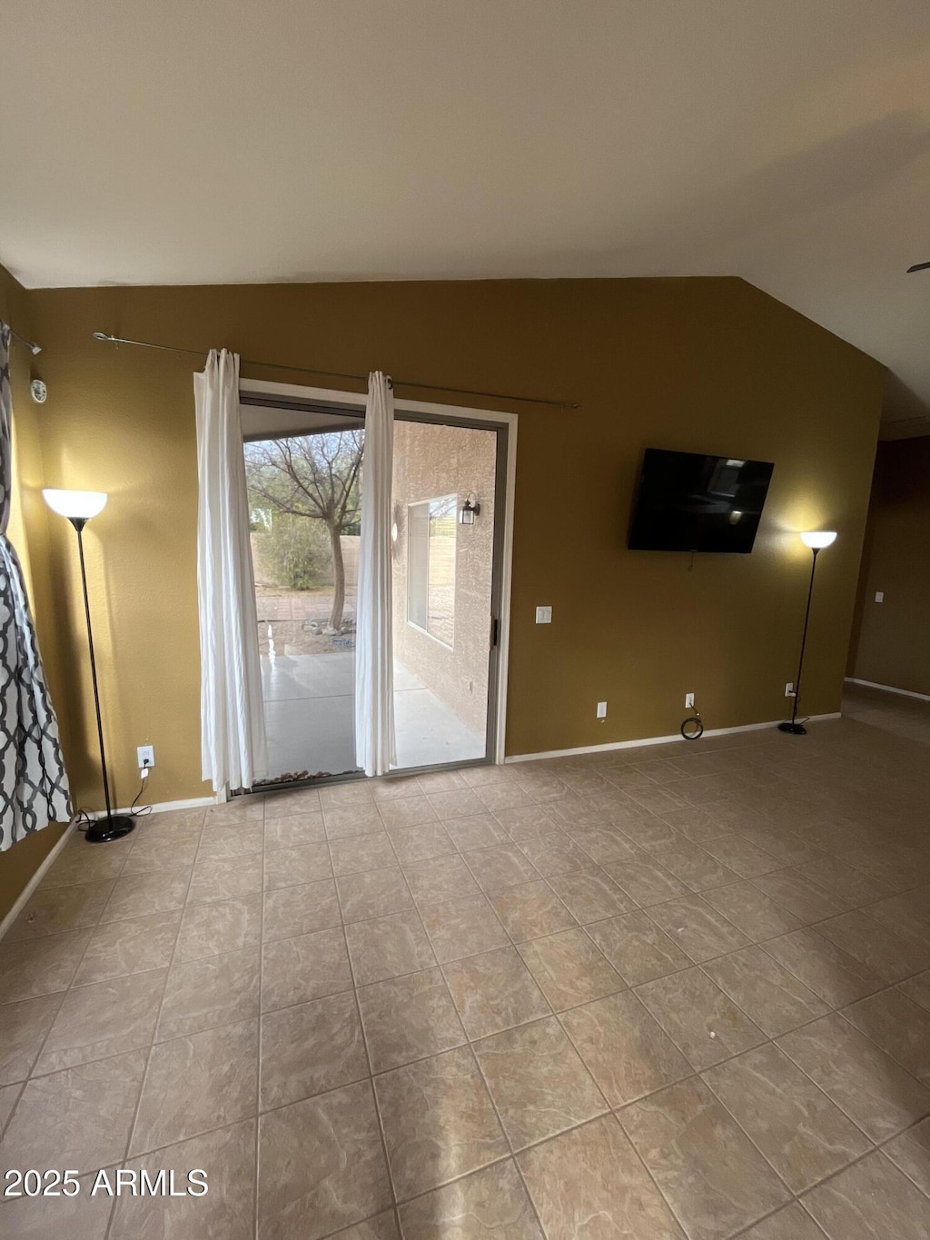 empty room with light tile patterned floors and vaulted ceiling