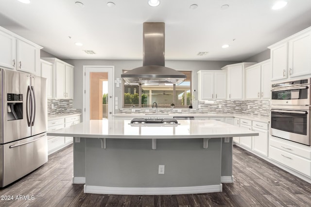 kitchen featuring white cabinetry, a center island, island exhaust hood, a kitchen bar, and appliances with stainless steel finishes