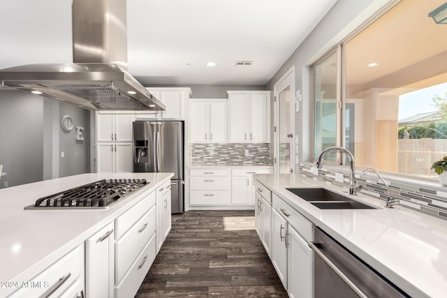 kitchen with appliances with stainless steel finishes, sink, wall chimney range hood, white cabinets, and dark hardwood / wood-style floors