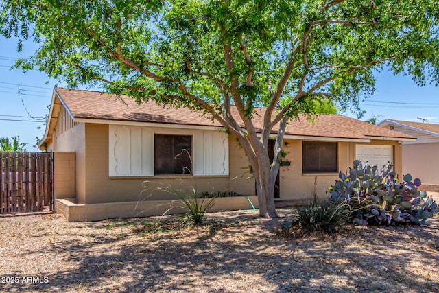 ranch-style house featuring fence, roof with shingles, and a garage
