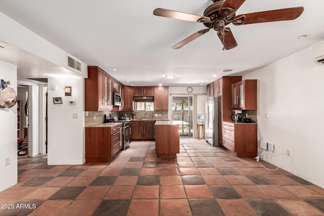 kitchen with visible vents, a kitchen island, glass insert cabinets, tasteful backsplash, and appliances with stainless steel finishes
