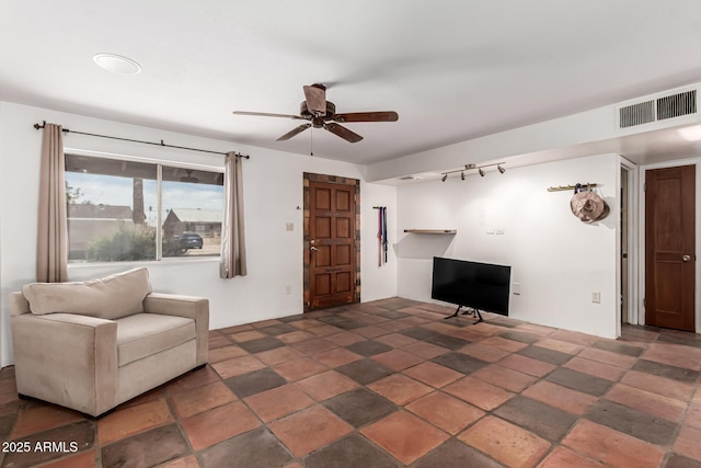 living area featuring visible vents, ceiling fan, stone finish floor, and track lighting