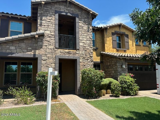 view of front facade featuring stone siding, a tile roof, and an attached garage