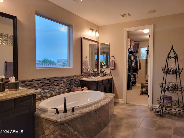 bathroom with a walk in closet, visible vents, vanity, a bath, and tile patterned floors