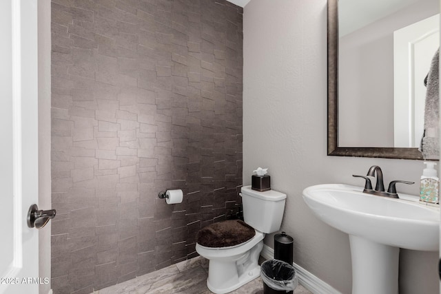 bathroom featuring toilet, baseboards, and a sink