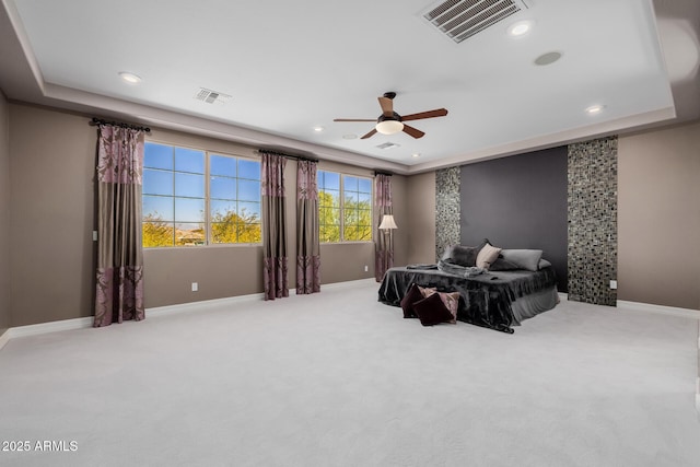 carpeted bedroom featuring baseboards, visible vents, and a raised ceiling