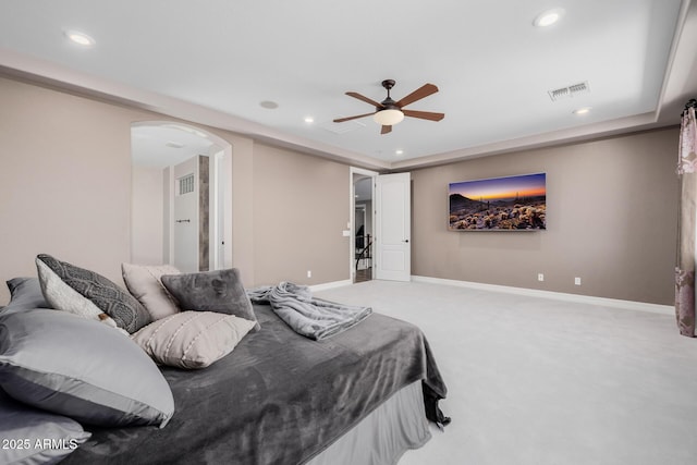 bedroom with arched walkways, a raised ceiling, visible vents, light carpet, and baseboards