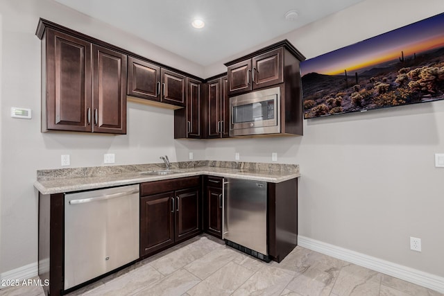 kitchen featuring dark brown cabinetry, recessed lighting, a sink, baseboards, and appliances with stainless steel finishes